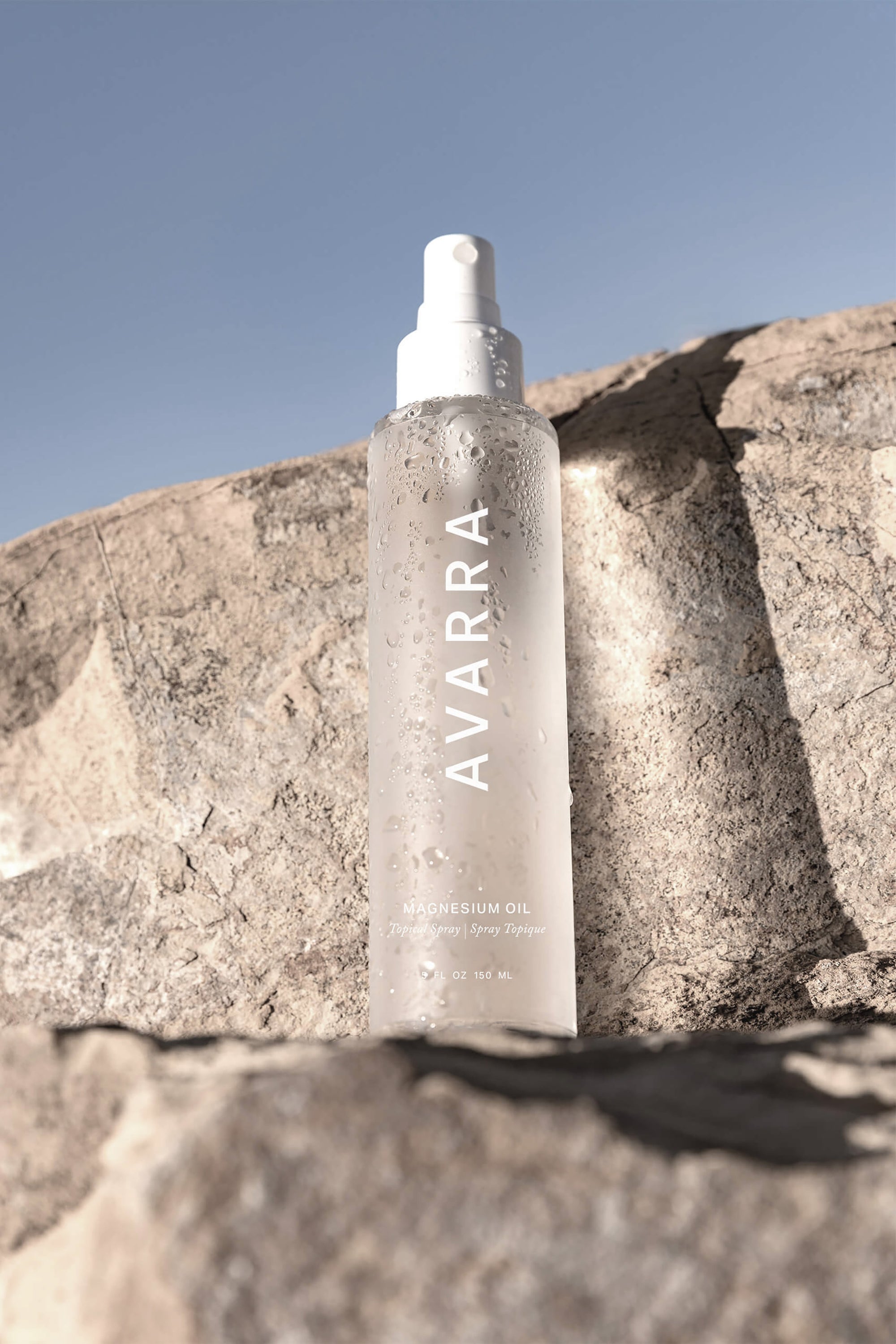 Avarra Magnesium Oil Spray Bottle on Rock with light on bottle