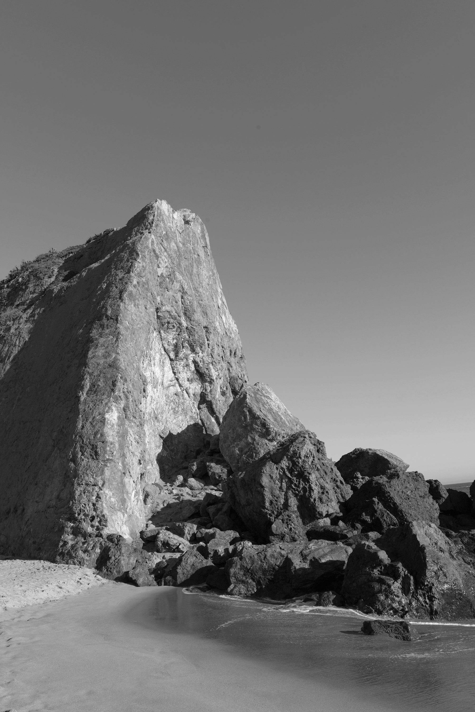 Monochrome image of a large rock formation on a beach
