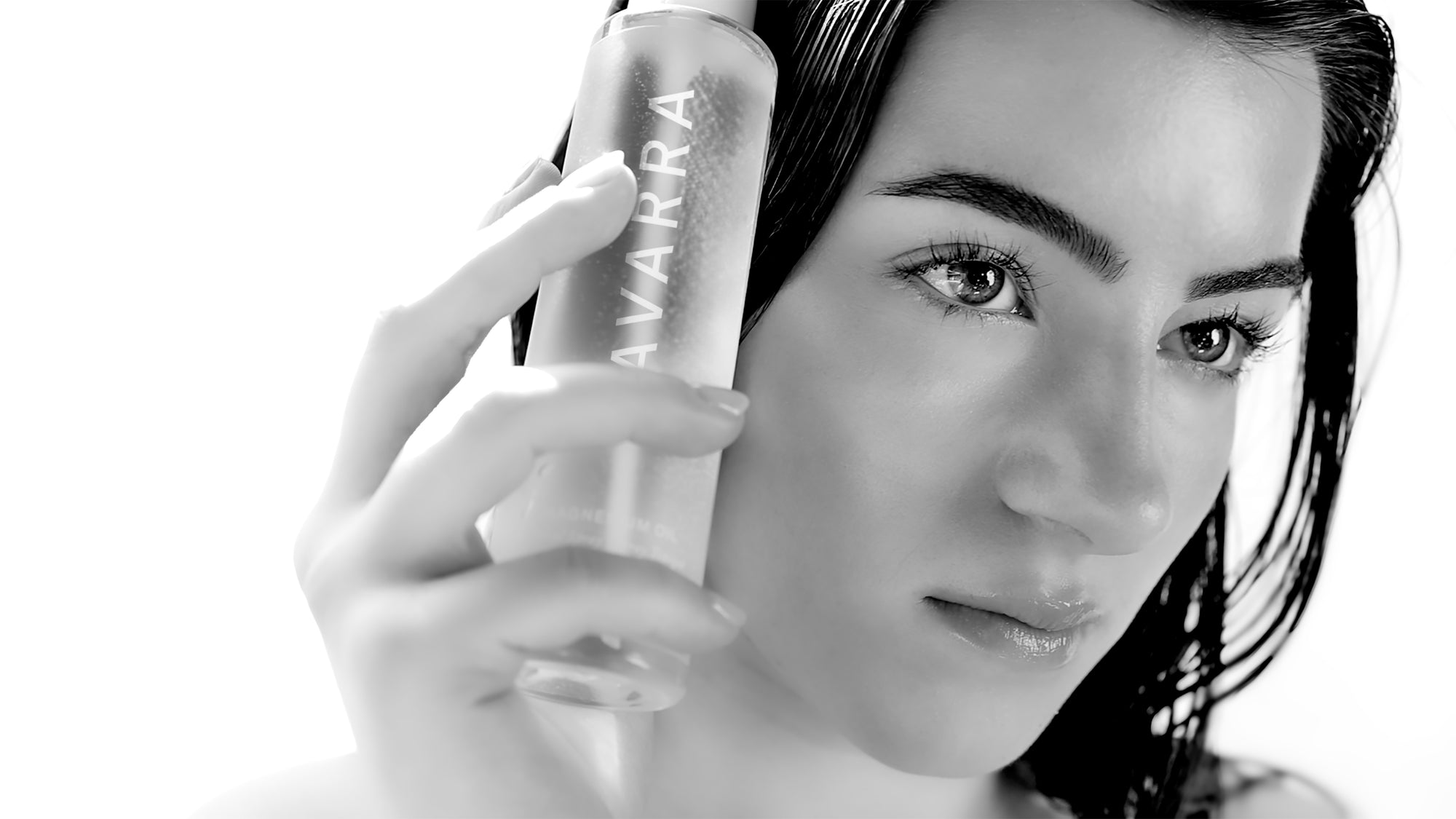 Woman holding a bottle of Avarra Magnesium Oil product with a white background